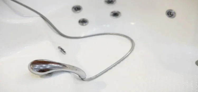 Chrome bathtub hand shower on white jetted tub with water and air jets